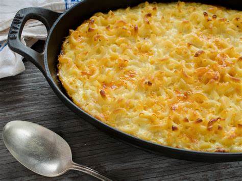 Mac and cheese sitting in a skillet on a table with a spoon nearby